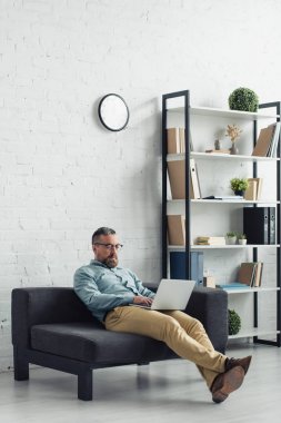 ofiste dizüstü bilgisayar kullanarak gömlek ve gözlük yakışıklı işadamı 