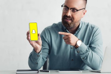 Kiev, Ukrayna - 27 Ağustos 2019: snapchat logolu akıllı telefonparmak ile işaret gömlek yakışıklı işadamı