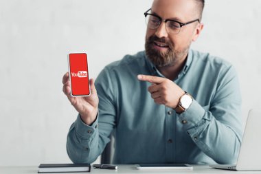 Kiev, Ukrayna - 27 Ağustos 2019: youtube logolu akıllı telefon parmak ile işaret gömlek yakışıklı işadamı
