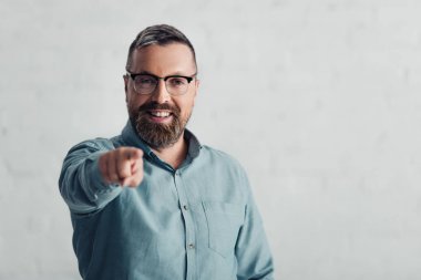 handsome businessman in shirt pointing with finger and looking at camera 
