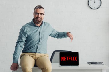 Kiev, Ukrayna - 27 Ağustos 2019: netflix logolu dizüstü bilgisayarda parmakla işaret eden gömlekli yakışıklı işadamı