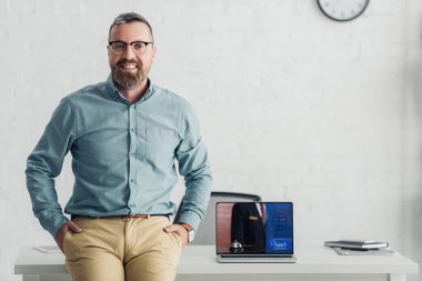 handsome businessman sitting on table near laptop with booking website 