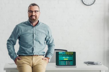 yakışıklı işadamı spor bahis web sitesi ile dizüstü bilgisayar yakınında masada oturan 