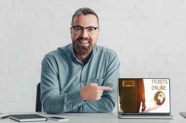 bilet online web sitesi ile dizüstü bilgisayar da parmak ile işaret gömlek yakışıklı işadamı 