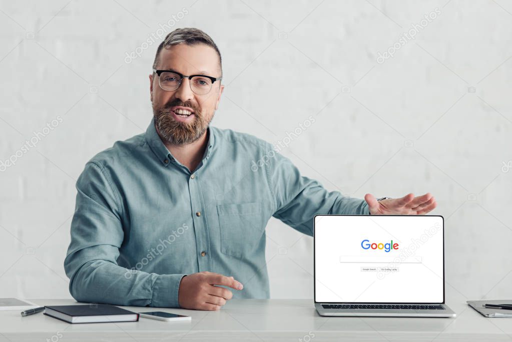 KYIV, UKRAINE - AUGUST 27, 2019: handsome businessman in shirt holding laptop with google logo