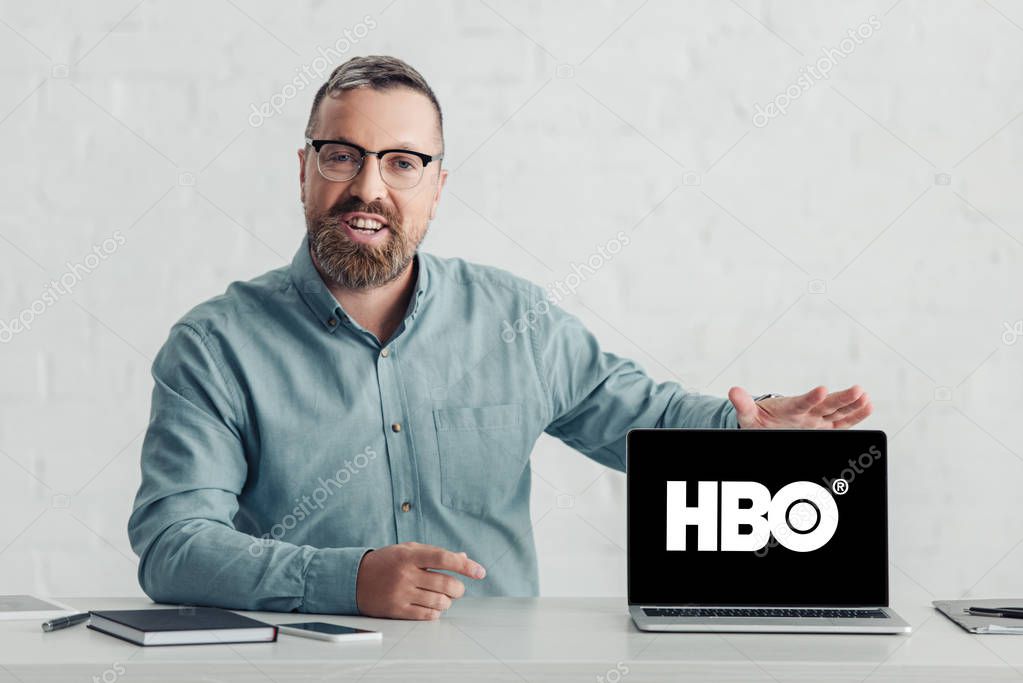 KYIV, UKRAINE - AUGUST 27, 2019: handsome businessman in shirt holding laptop with hbo logo