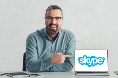 Kiev, Ukrayna - 27 Ağustos 2019: skype logolu dizüstü bilgisayarda parmakla işaret eden gömlekyakışıklı işadamı