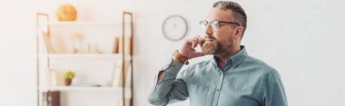 panoramic shot of handsome businessman in shirt and glasses talking on smartphone 