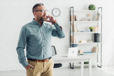ofiste akıllı telefon konuşurken gömlek ve gözlük yakışıklı işadamı 