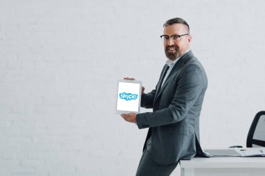 Kiev, Ukrayna - 27 Ağustos 2019: Skype logolu dijital tablet tutan resmi giyim yakışıklı işadamı