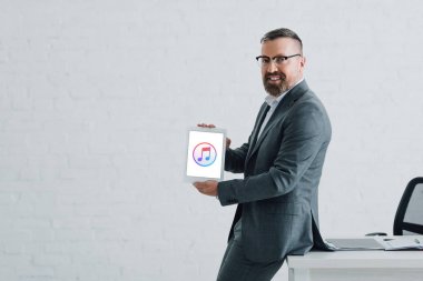 Kiev, Ukrayna - 27 Ağustos 2019: Apple Müzik logolu dijital tablet tutan resmi giyim yakışıklı işadamı