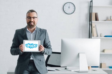 Kiev, Ukrayna - 27 Ağustos 2019: Skype logolu dijital tablet tutan resmi giyim yakışıklı işadamı