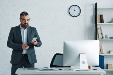 resmi giyim ve gözlük akıllı telefon tutan yakışıklı işadamı 