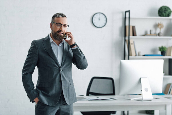 handsome businessman in formal wear and glasses talking on smartphone 