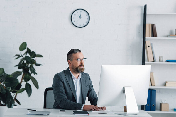 handsome businessman in formal wear and glasses using computer 