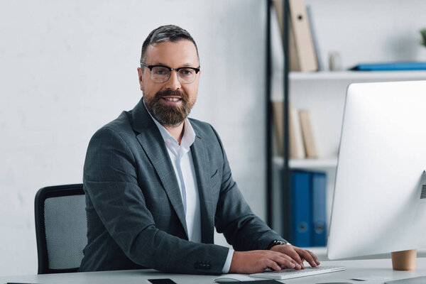 handsome businessman in formal wear smiling and looking at camera 