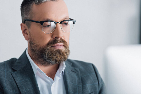 selective focus of handsome businessman in formal wear and glasses looking away 