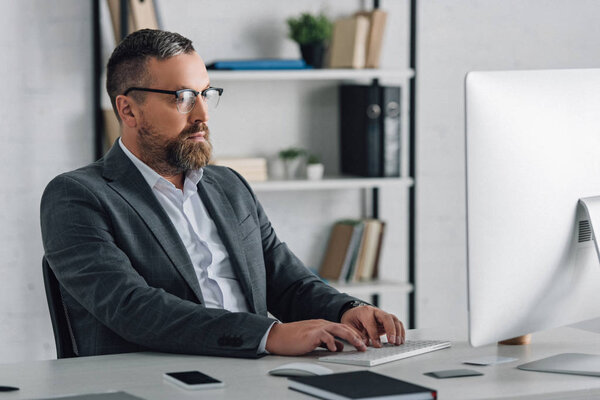 handsome businessman in formal wear and glasses using computer 