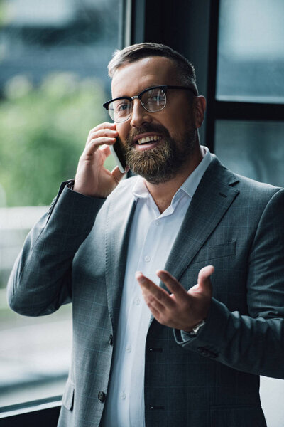 handsome businessman in formal wear and glasses talking on smartphone 