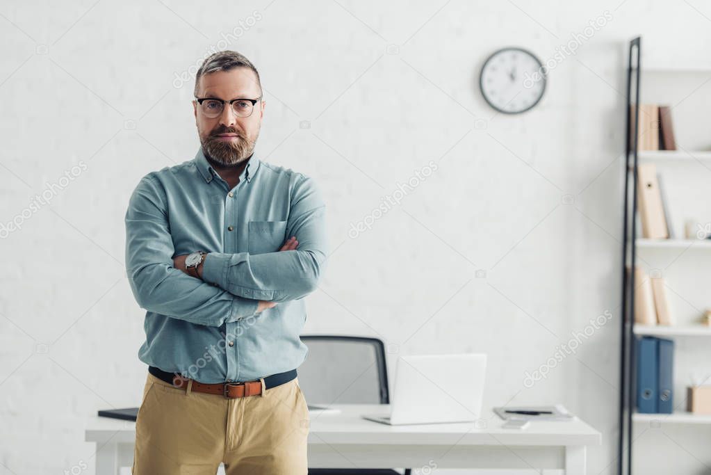 handsome businessman in shirt and glasses looking at camera in office 