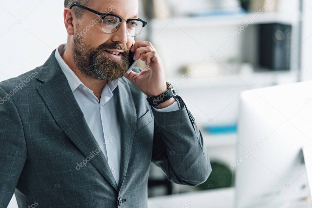 handsome businessman in formal wear and glasses talking on smartphone 