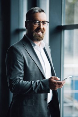 resmi giyim ve gözlük akıllı telefon tutan yakışıklı işadamı 