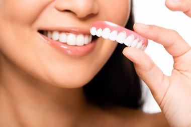 cropped view of woman holding false teeth isolated on white clipart