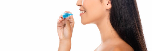 side view of smiling naked asian woman holding mouth guard isolated on white, panoramic shot