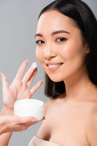 微笑赤裸裸的亚洲附近妇女拿着化妆品奶油隔离在灰色 — 图库照片