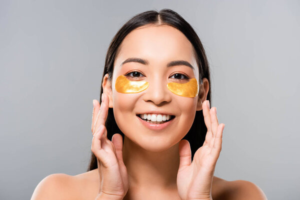 happy naked asian woman with eye patches on face isolated on grey