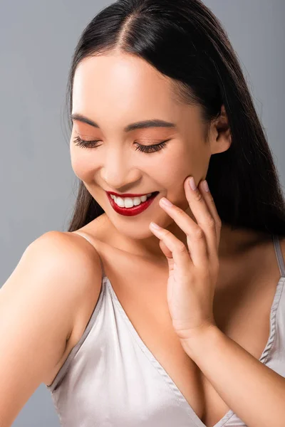 灰色に隔離された赤い唇を持つサティンドレスで美しい笑顔のアジアの女性 — ストック写真