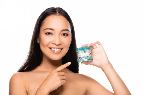 smiling naked asian woman pointing with finger at jaw model isolated on white