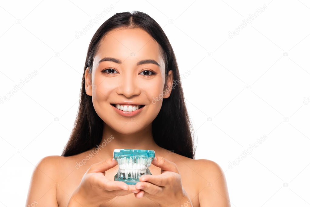 smiling naked asian woman holding jaw model isolated on white