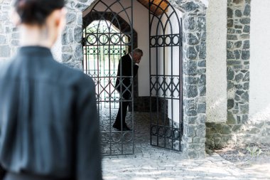 selective focus of upset man covering face in building near woman  clipart