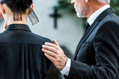 cropped view of man touching woman on funeral  clipart