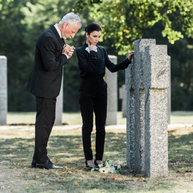 gri saçlı üzgün adam ve mezarların yanında duran çekici kadın 