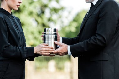 cropped view of senior man and woman holding mortuary urn  clipart