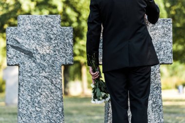 çiçeklerle mezarlar yakınında duran yaşlı adam kırpılmış görünümü 