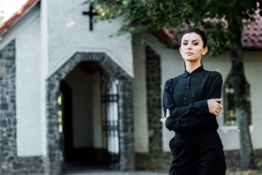kilisenin yakınında çapraz kolları ile ayakta çekici kadın 