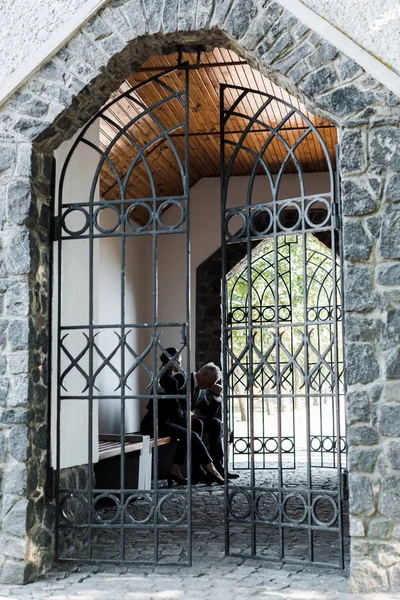 Upset Man Woman Sitting Metallic Gates Cemetery — Stock Photo, Image