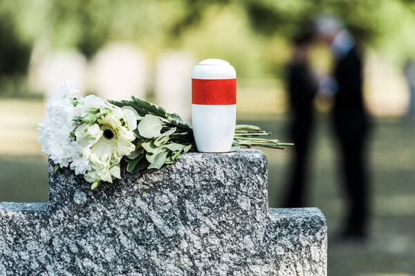 selective focus of flowers and mortuary urn on tomb 