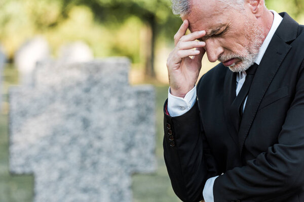 upset senior man touching face on funeral 