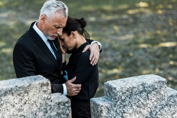 墓の近くで女性を抱きしめる先輩男性の選択的焦点 — ストック写真