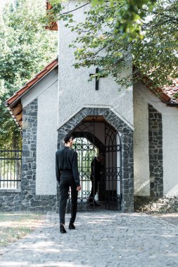 ağaçların yakınındaki kiliseye yürüyen kadının arka görünümü 