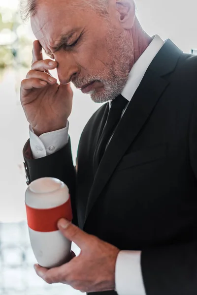 Verärgerter Älterer Mann Berührt Gesicht Und Hält Urne Der Hand — Stockfoto