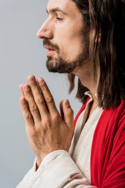 side view of bearded man with praying hands isolated on grey  clipart