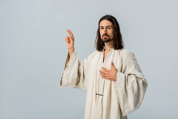 bearded man praying with hand on chest isolated on grey 