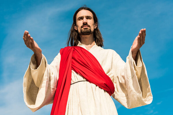 low angle view of bearded man with outstretched hands against sky 
