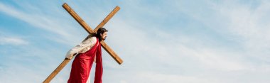 panoramic shot of bearded man walking with wooden cross  clipart