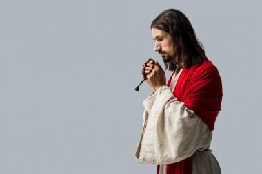 religious man holding rosary beads while praying isolated on grey 